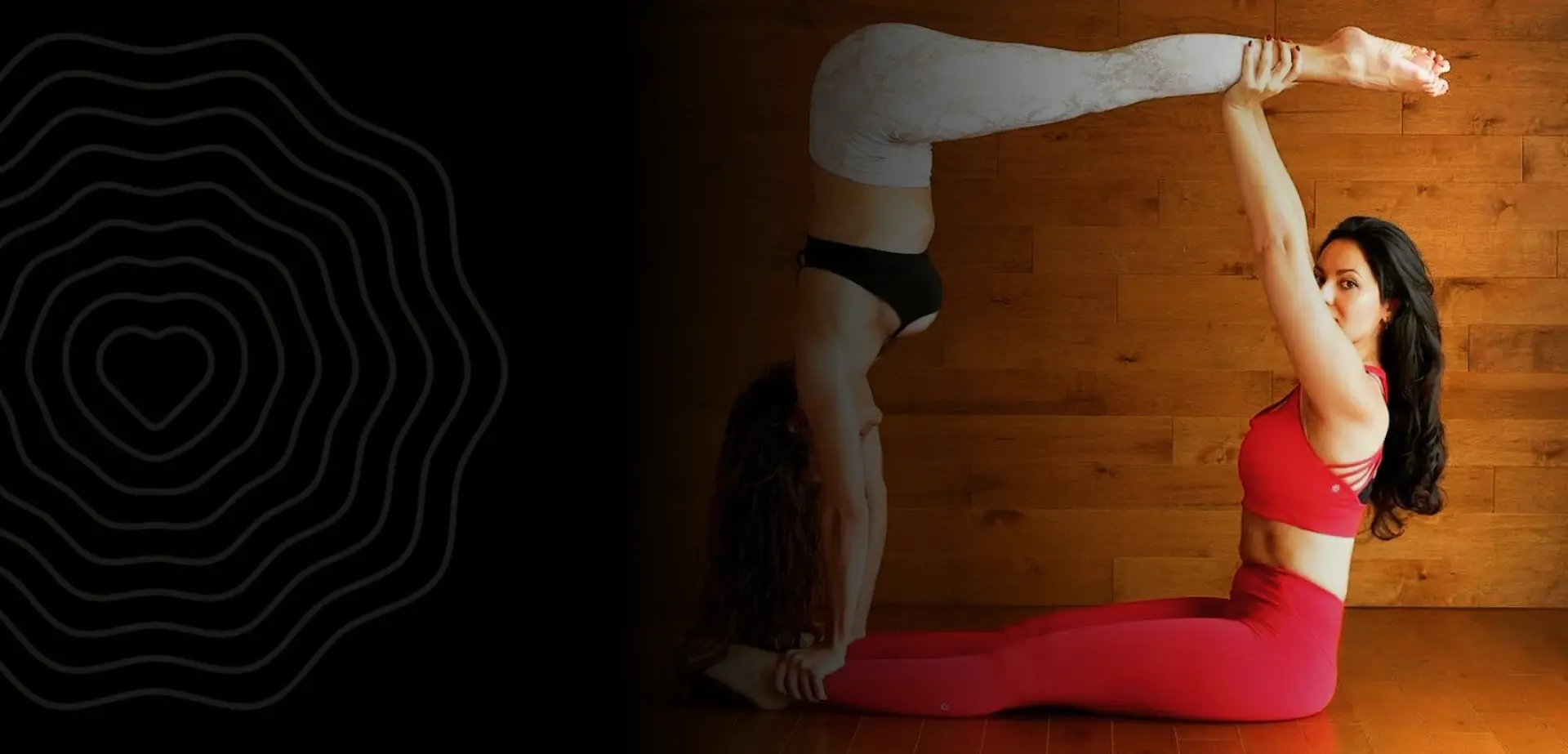 Two women practising partner yoga against a warm wooden wall